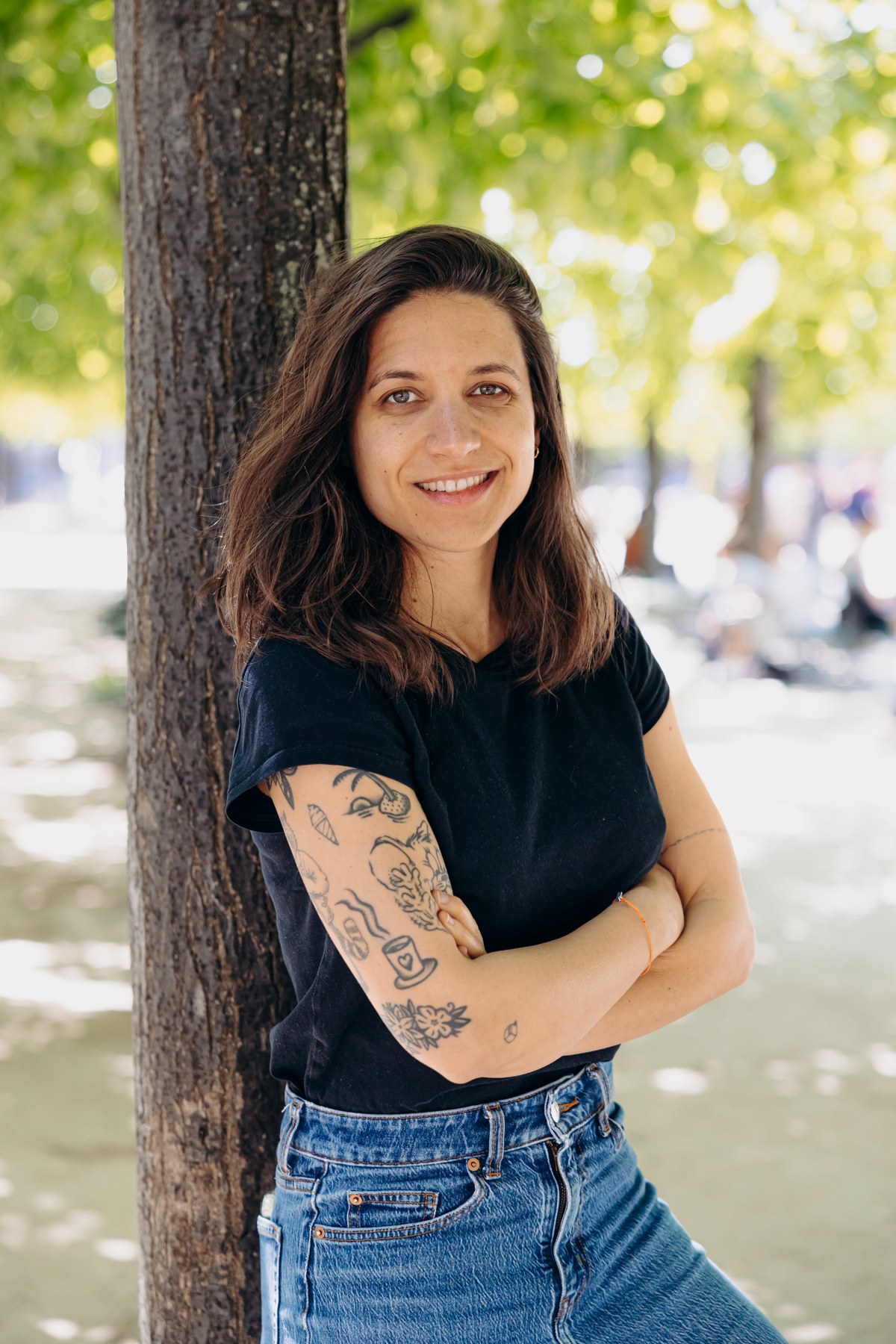 Sarah en haut noir, debout près d’un arbre